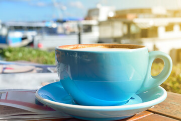 Large cup of morning latte in front of sunny marina