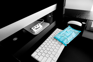 Coronavirus. A medical mask lies near a laptop in the workplace. Sanitizer on table