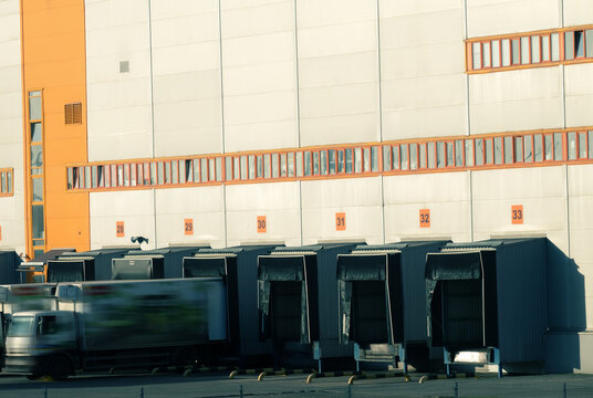 Dock-shelters and dock-levellers on the motor terminal, load-handling equipment. Images of unloading trailers blurred for indeterminacy of car brand