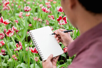 Woman taking notes in a white flower garden