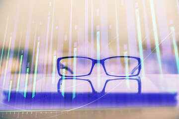 Financial graph hologram with glasses on the table background. Concept of business. Double exposure.