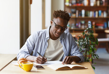 Fototapeta na wymiar Young African American man studying in modern cafe