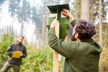 Trainee and forester inspect bark beetle trap