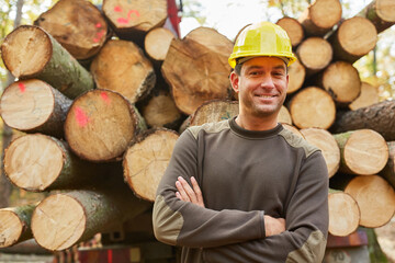 Smiling lumberjack transporting long wood