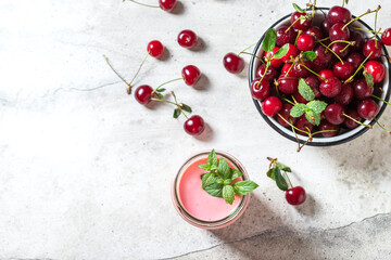Yogurt with cherry, mint and and fresg berries on a light concrete background. Summer healthy dessert with berries.