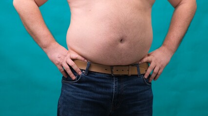 male with a big belly shows his fat on a green screen. The concept of healthy eating and losing...