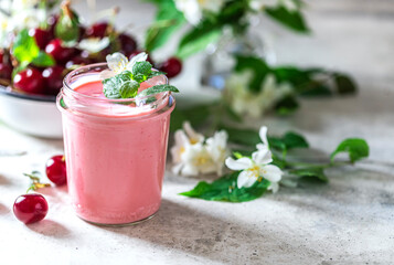 Yogurt with cherry, mint and and fresg berries on a light concrete background. Summer healthy dessert with berries.
