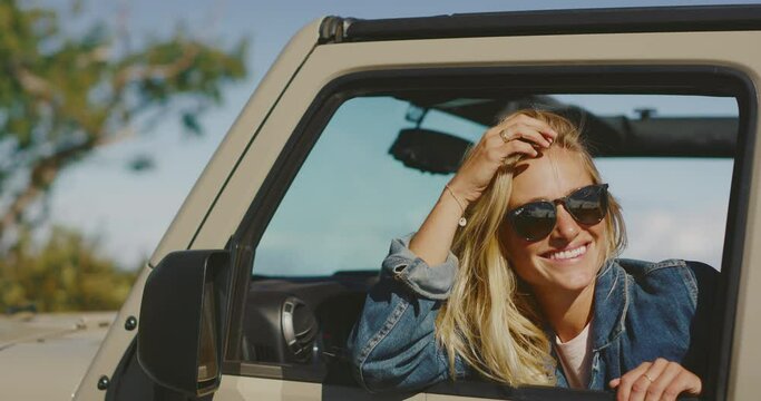 Happy beautiful young woman laughing in off road truck, exploring beautiful mountain back country