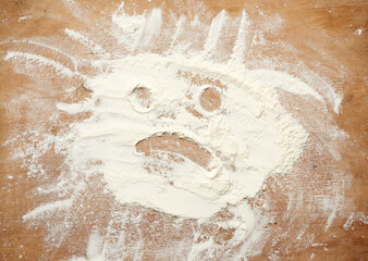sprinkled white wheat flour on a brown wooden table