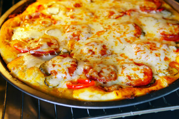 fried homemade pizza in the oven. cook at home. cooking pizza with ingredients cucumbers, tomatoes, cheese, spices sauce, salami pepperoni.