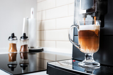 glass cup with hot cappuccino with foam prepared in the coffee machine