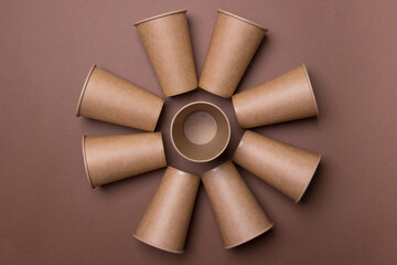 flower made of brown eco-friendly cardboard cups on brown colored paper background. top view. close-up. mock-up