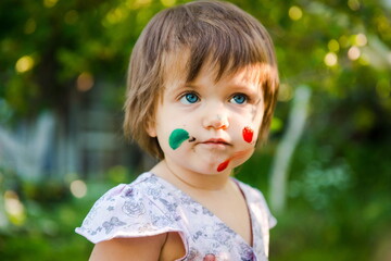 little girl is drawing. Young artist. Painting.  Funny girl in the park. activity for children. funny girl painted her face. Dirty face 