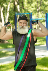 Naklejka premium Old man doing fitness exercises with elastic resistance band.Bearded senior training with rubber band. Workout ,sports, healthy lifestyle concept.