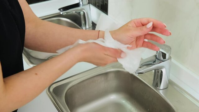 Caucasian woman cleaning her hands with a tissue on the background of the sink in the dental clinic or public place. Healthcare and medical concept.