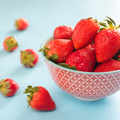 colorful ripe strawberries in a bright bowl on a blue background