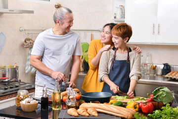 Happy family of mother father and daughter cooking in kitchen making healthy food together feeling fun