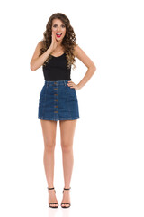 Fototapeta premium Sexy Woman In Jeans Mini Skirt And High Heels Is Talking With Hand On Chin