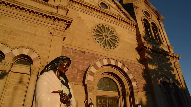 Native American bronze statue monument with The Cathedral Basilica of Saint Francis of Assisi, in the background.