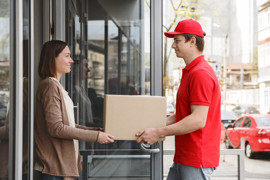Customer care home delivery. Girl takes cardboard box from courier