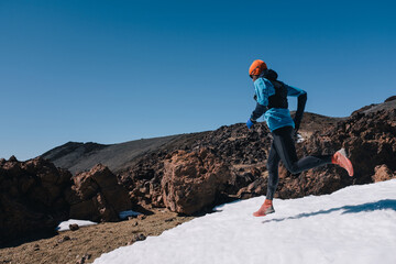 Trail running man runner in white winter mountains on snow.