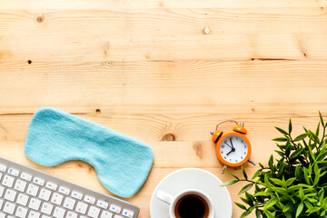 Hard exhausing work concept. Sleep mask on wooden office desk top view copyspace