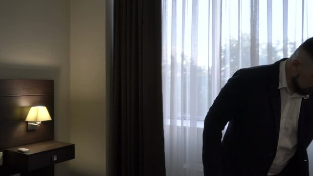 Mature businessman in a hotel room gets dressed.