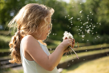 Sommer  - Kind pustet an Pusteblumen