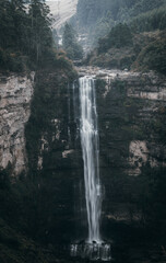 A waterfall in a forest surrounded by rocks and trees