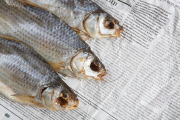MOSCOW / RUSSIA - 13/05/2020 close up top view shot of three dried salted vobla (Caspian Roach) fish lying on a Russian newspaper background