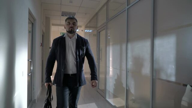 Mature businessman leaves a hotel room walks along the corridor of the hotel to the elevator