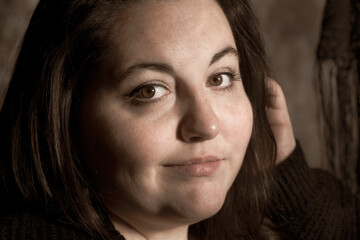 Vintage photo style image of Plus size BBW brunette woman posing in a low key