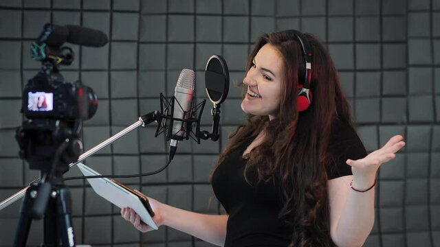 Attractive woman blogger speaks about professional voice over and dubbing, she recording video about it for her online vlog or some tutorial courses. Woman recording interest content for audience