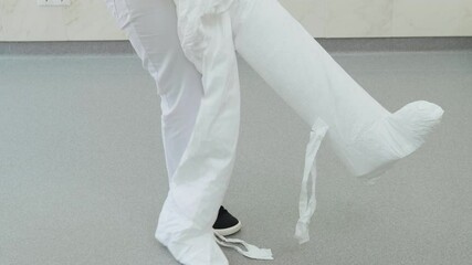 The doctor wears a white protective suit on the legs in the clinic or hospital. Dentist prepares to receive patients during coronavirus pandemic.