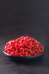 Close up of pomegranate seeds in bowl on dark background. Selective Focus