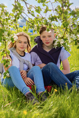Fototapeta premium A young couple a young man and a girl sit on a blooming Apple tree