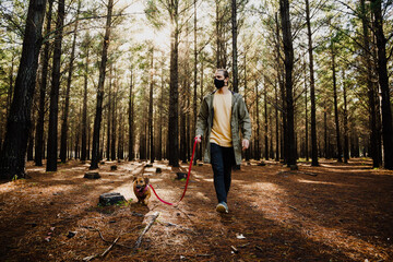 Fototapeta premium Caucasian male walking the dog during covid19 pandemic with mask on, alone