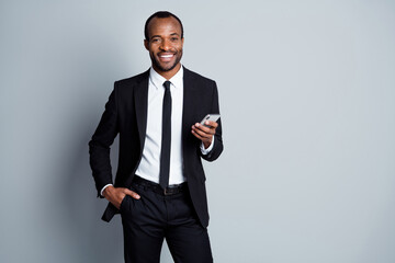 Portrait of his he nice attractive cheerful cheery chic classy luxury imposing guy employee banker wearing suit holding in hands using device posing isolated over grey pastel color background