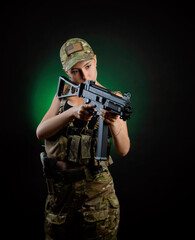 a sexy girl in military airsoft overalls poses with a assault rifle on a dark background