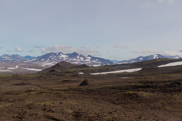 Daytime view of the stony wasteland in daytime; View of the volcano on the horizon in clear weather