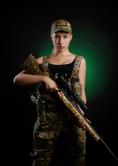 a sexy girl in military airsoft overalls poses with sniper rifle on a dark background