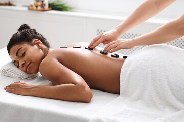 Healthy hot stone massage for tranquil black woman