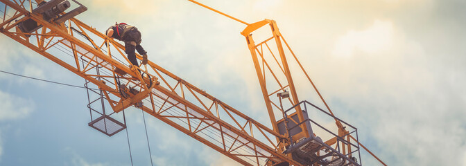 heavy equipment and crane mechanic with white helmet and harness repairing a crane with hand tools © JuanFrancisco