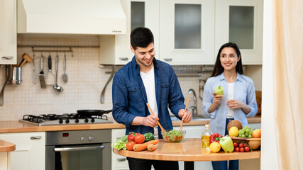 Happy couple preparing salad together at home