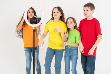 Obraz premium A group of children bloggers shoot video on the phone. Selfies The phone is mounted on a modern round lamp with a tripod.