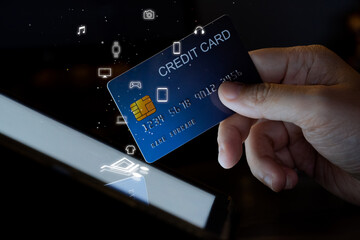 Finger hold credit card touch on Tablet screen with shopping icon. Concept for online shopping mobile phone technology and device.