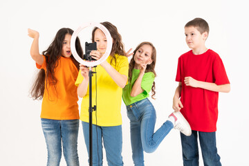 Obraz premium A group of children bloggers shoot video on the phone. Selfies The phone is mounted on a modern round lamp with a tripod.