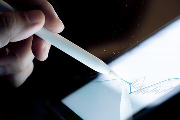 Hand use  pen stylus touch business graph  on Tablet screen Mock up with light. Concept for mobile phone technology and business look.