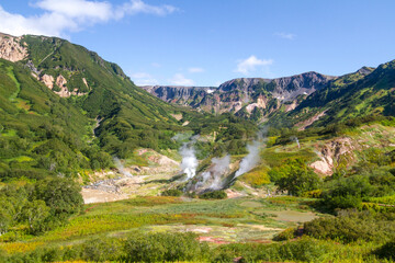 Fototapeta premium Daytime view in clear sunny weather of the valley of geysers. Mountains and volcanoes are visible on the horizon.
