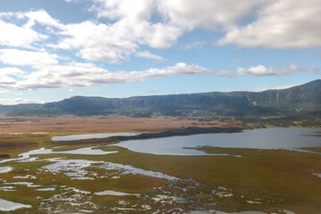 Daytime view in clear sunny weather of the valley of geysers. Mountains and volcanoes are visible on the horizon.